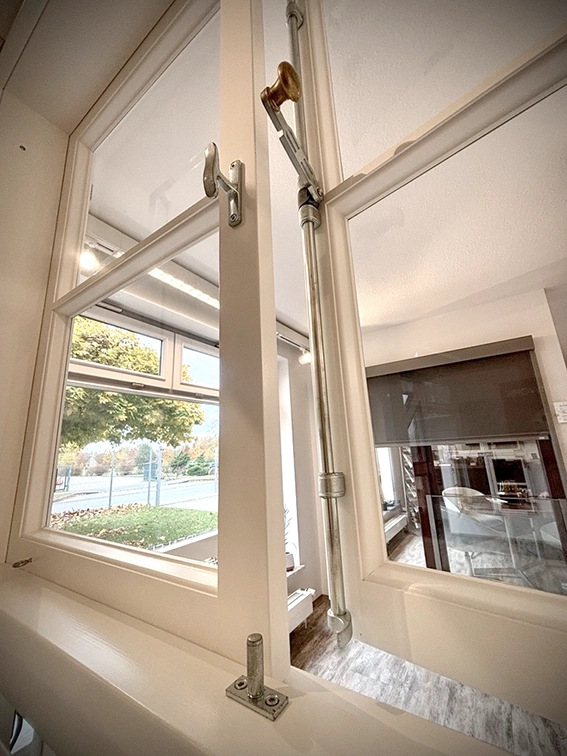 Fensterdrehstange an einem Holzfenster in weiß nach aussen öffnend