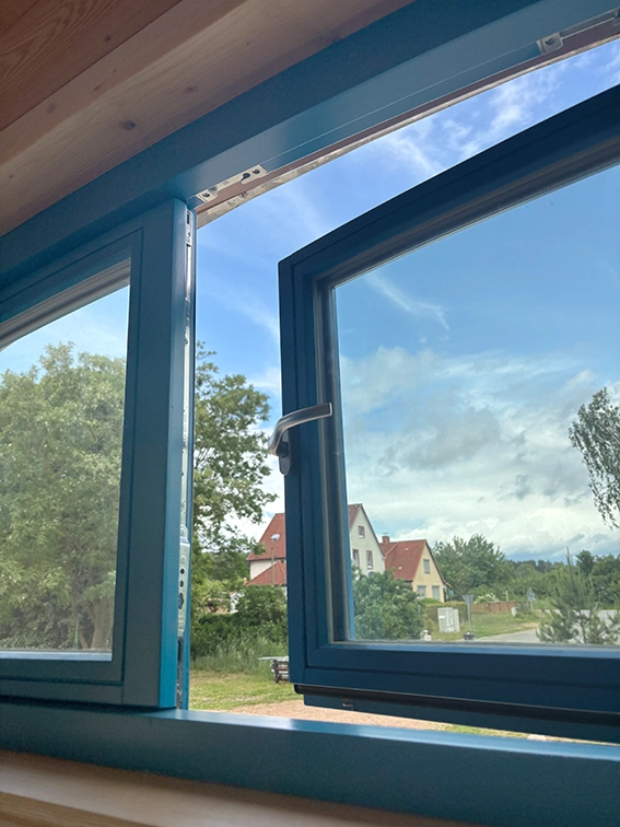 Blaues Holzfenster im Zirkuswagen nach aussen öffnend.