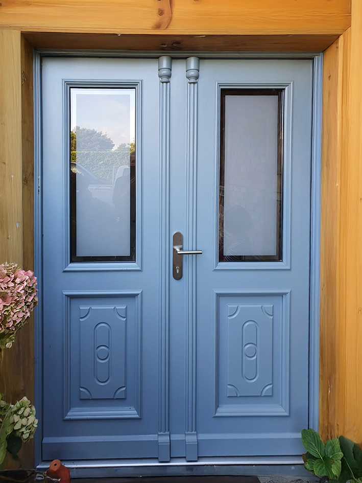 Eingangstür in Blau mit Zierelementen und Satinatoglas