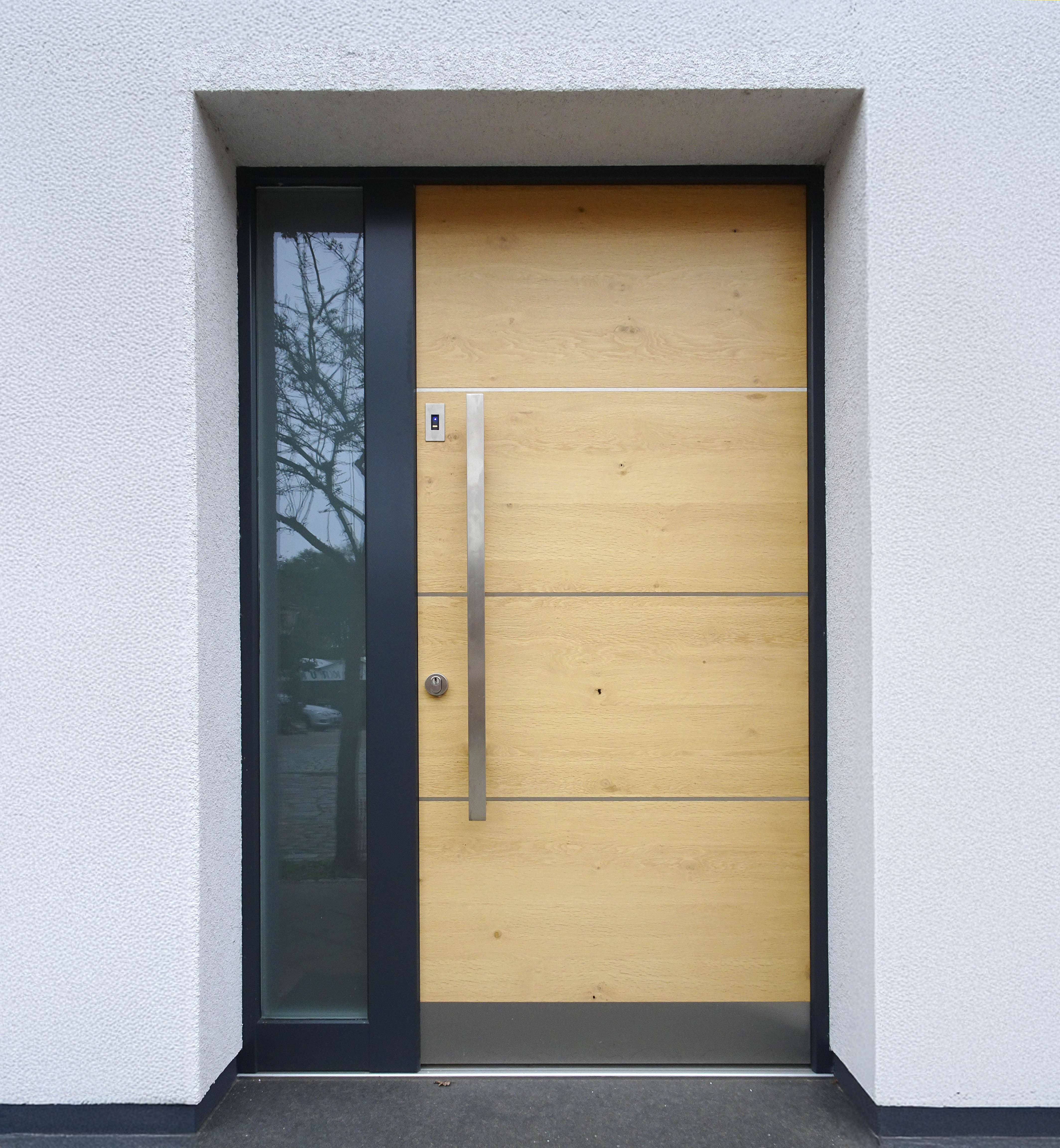 Eingebaute Moderne Haustür mit Echtholzoberfläche, Edelstahllisenen und einem Seitenteil aus Glas.