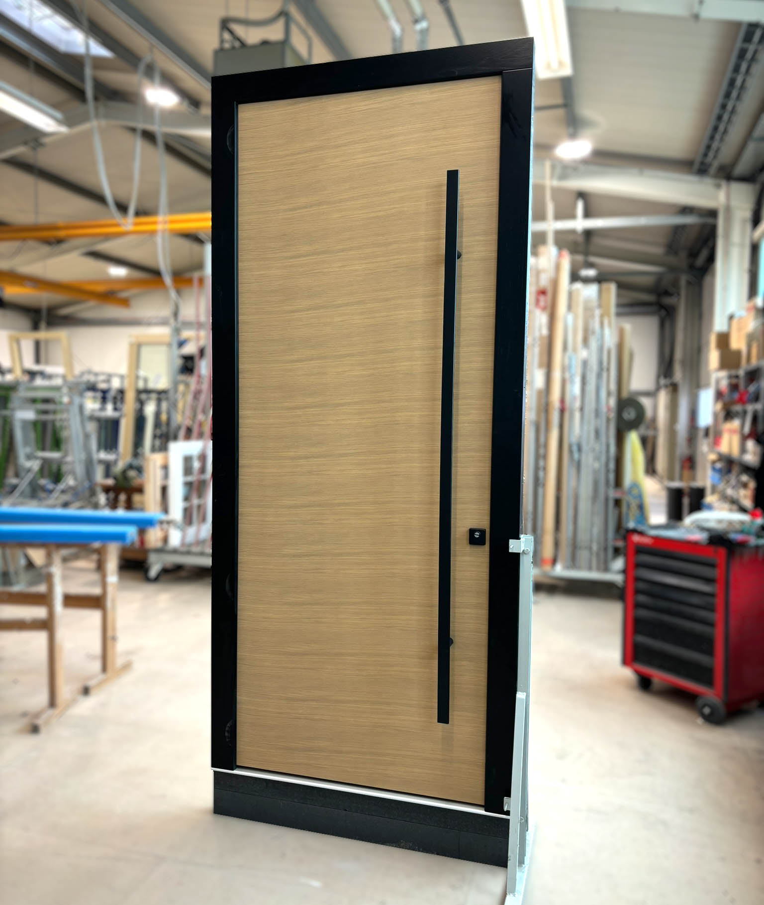 Eingangstür aus Holz mit schwarzer Griffstange und kompletter Holzoberfläche aus RedGrandis.