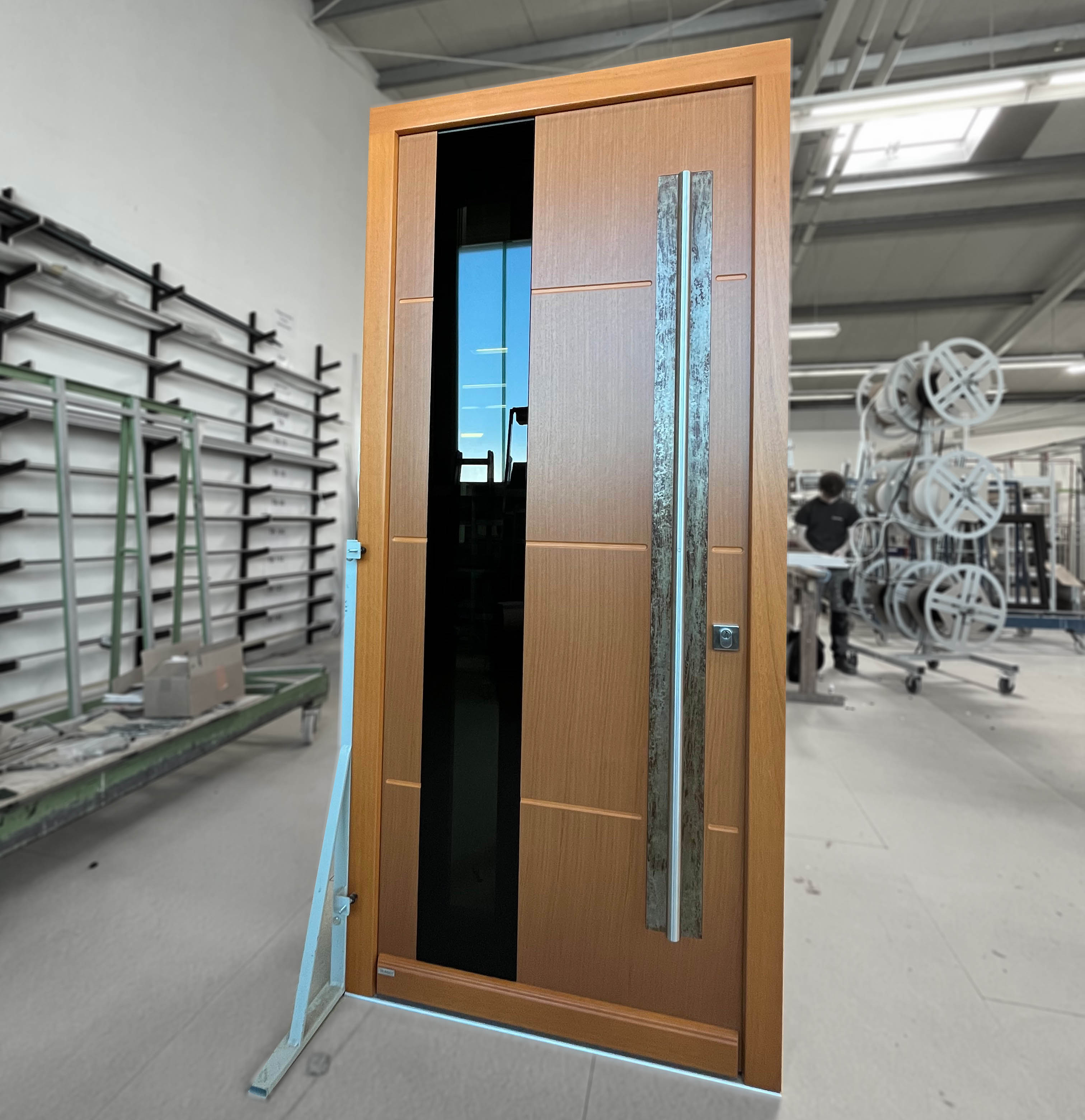 Exklusive Holzeingangstür aus RedGrandis mit schwarzem Lischtausschnitt, Bronzeapplikation hinter dem modernen Griff.