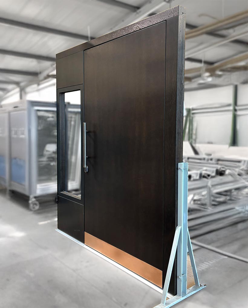 Exklusive Eingangstür aus Holz, Echtholzoberfläche mit Briefkastensystem und bronzefarbender Applikation.